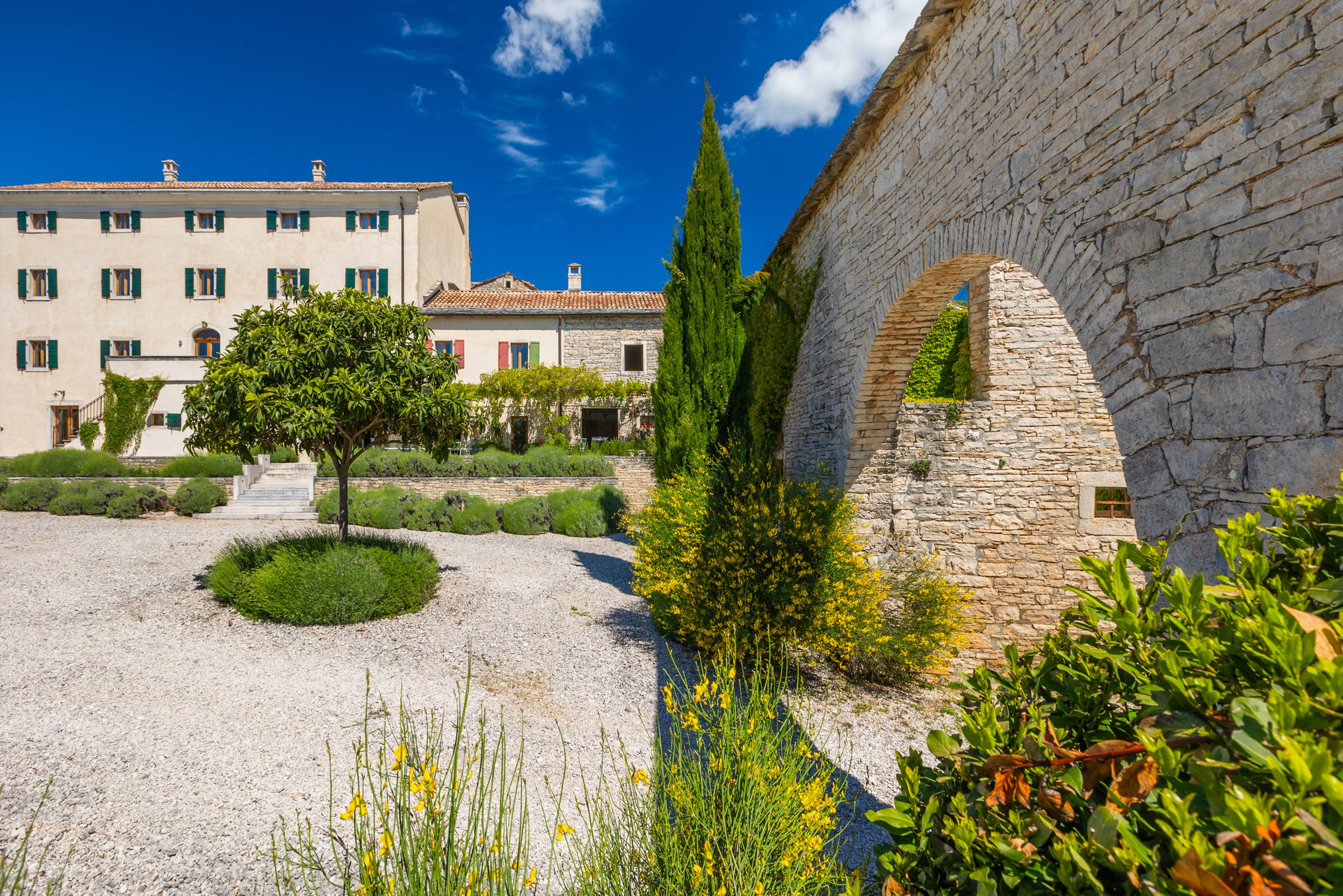 casa ceppi istria croatia garden courtyard topiary tree stone archway wall