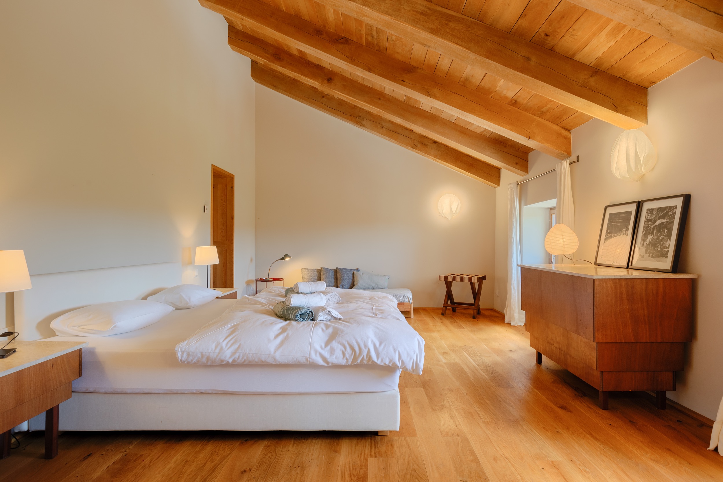 casa ceppi istria croatia interior bedroom sloped wood beam ceiling white bed dresser artwork